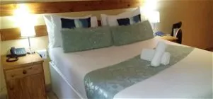 Neatly made bed with decorative pillows and towels in a cozy bedroom