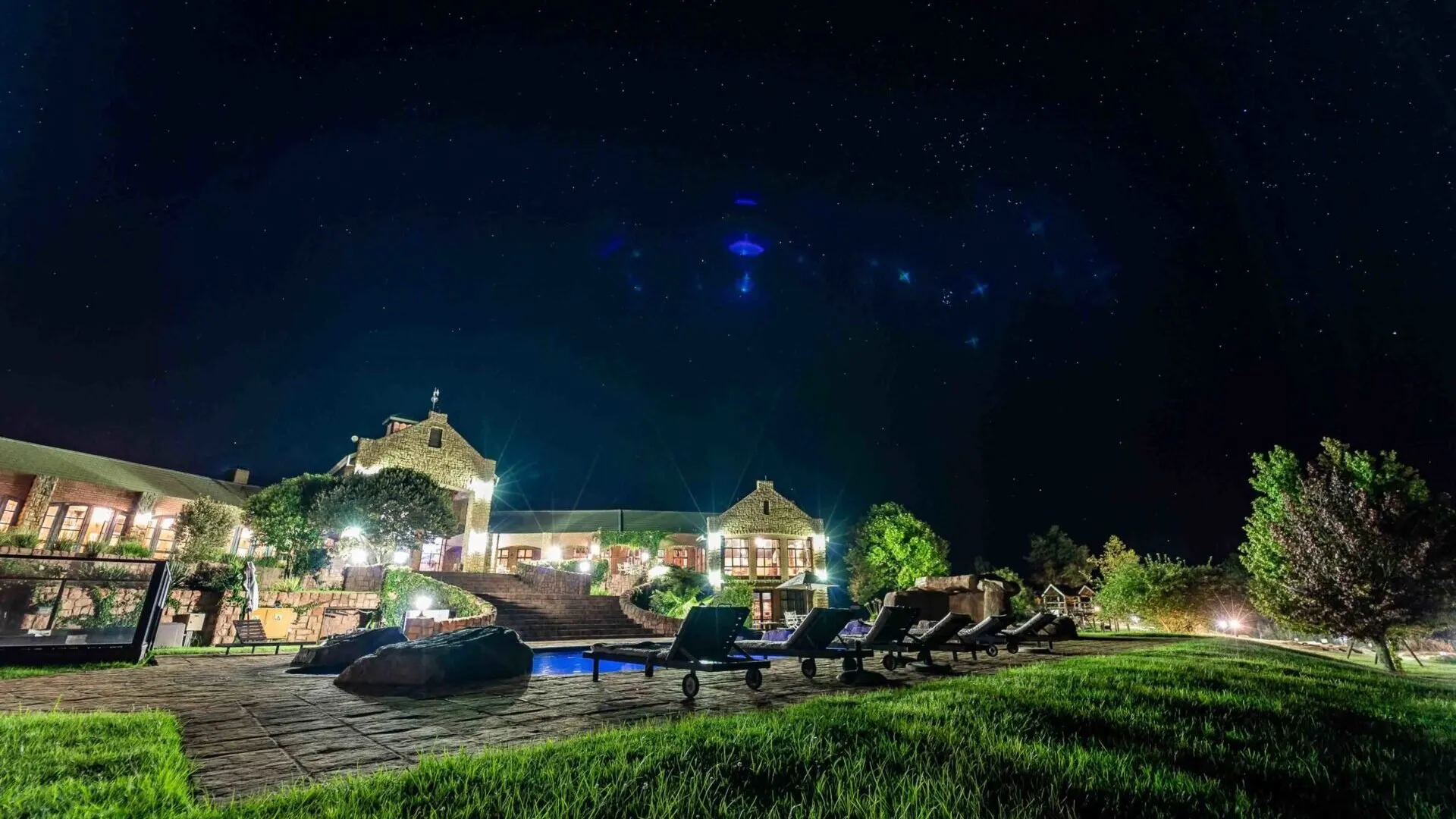 Night view of a resort with lounge chairs and a starry sky