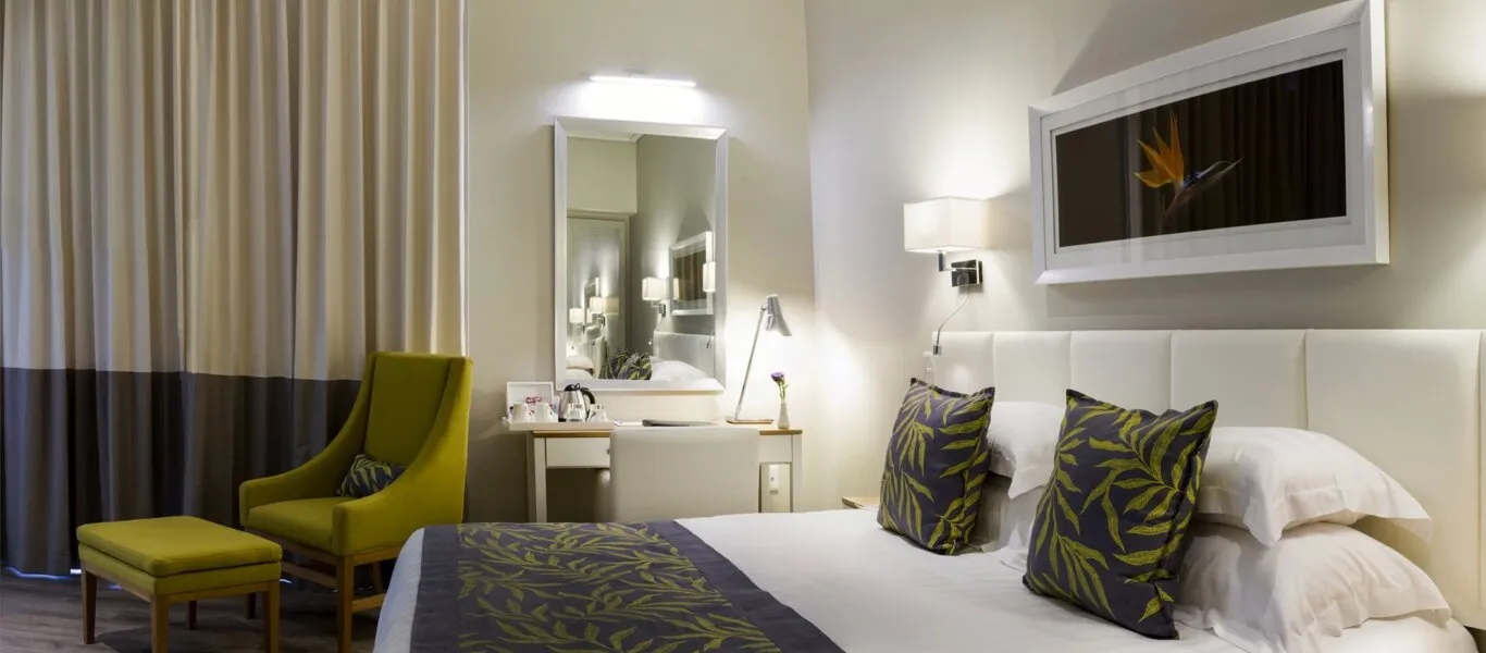 Modern hotel room with bed armchair desk and large mirror