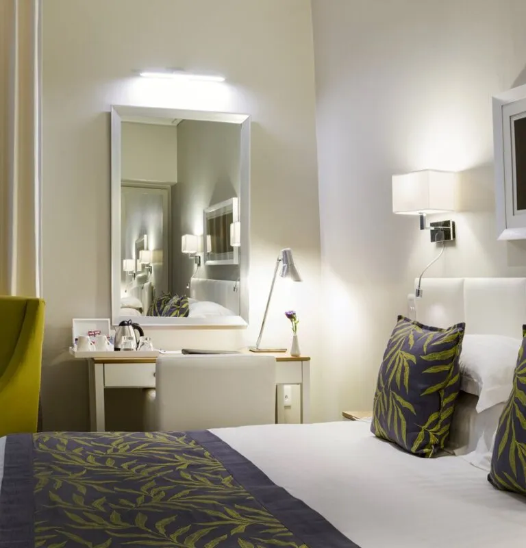 Modern hotel room with bed desk mirror and lamp