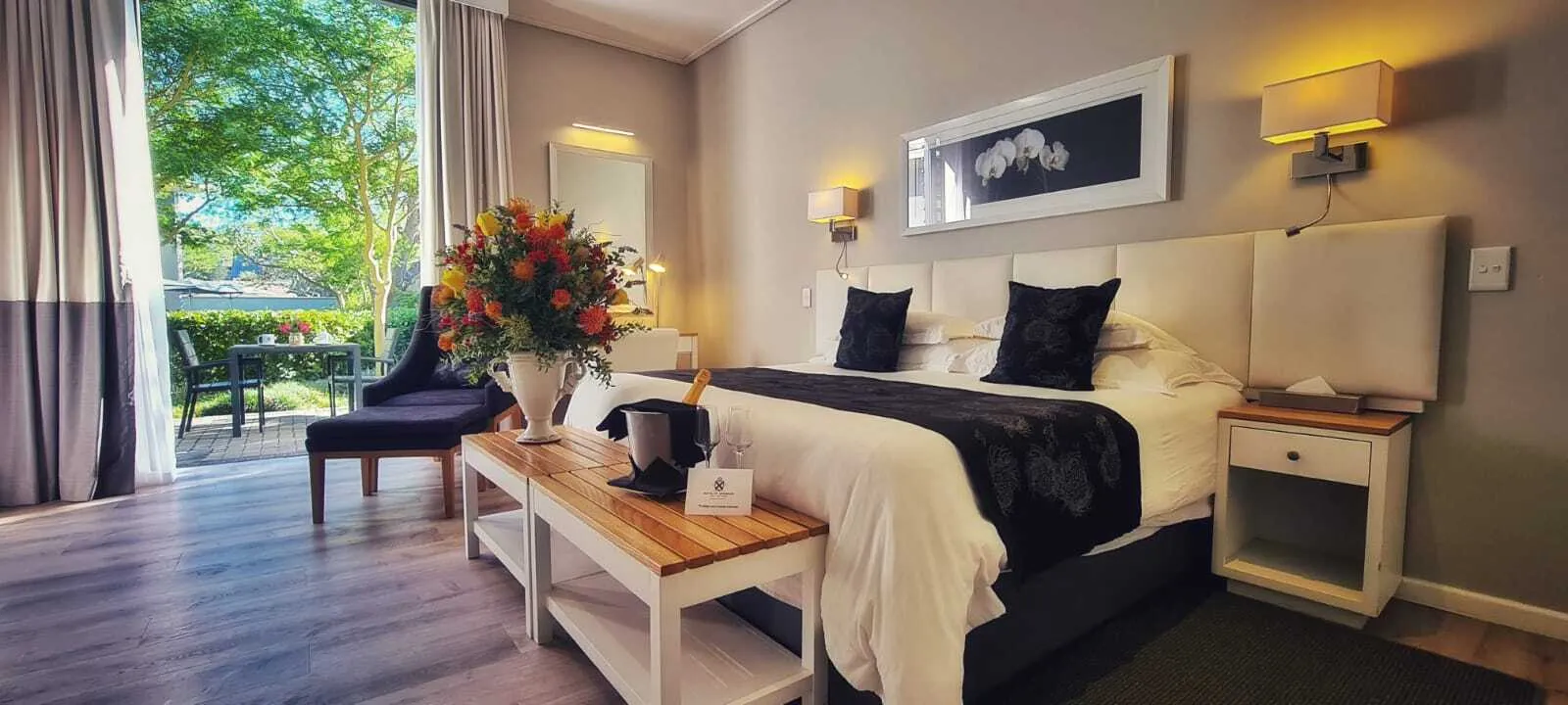 Modern bedroom with large bed white furniture and view of outdoor greenery