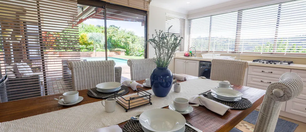 Dining table set for four in a bright kitchen with a garden view