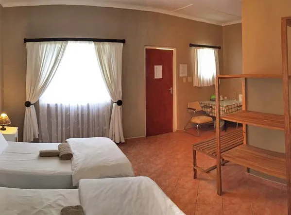 Bedroom with two beds window with curtains door and wooden furniture