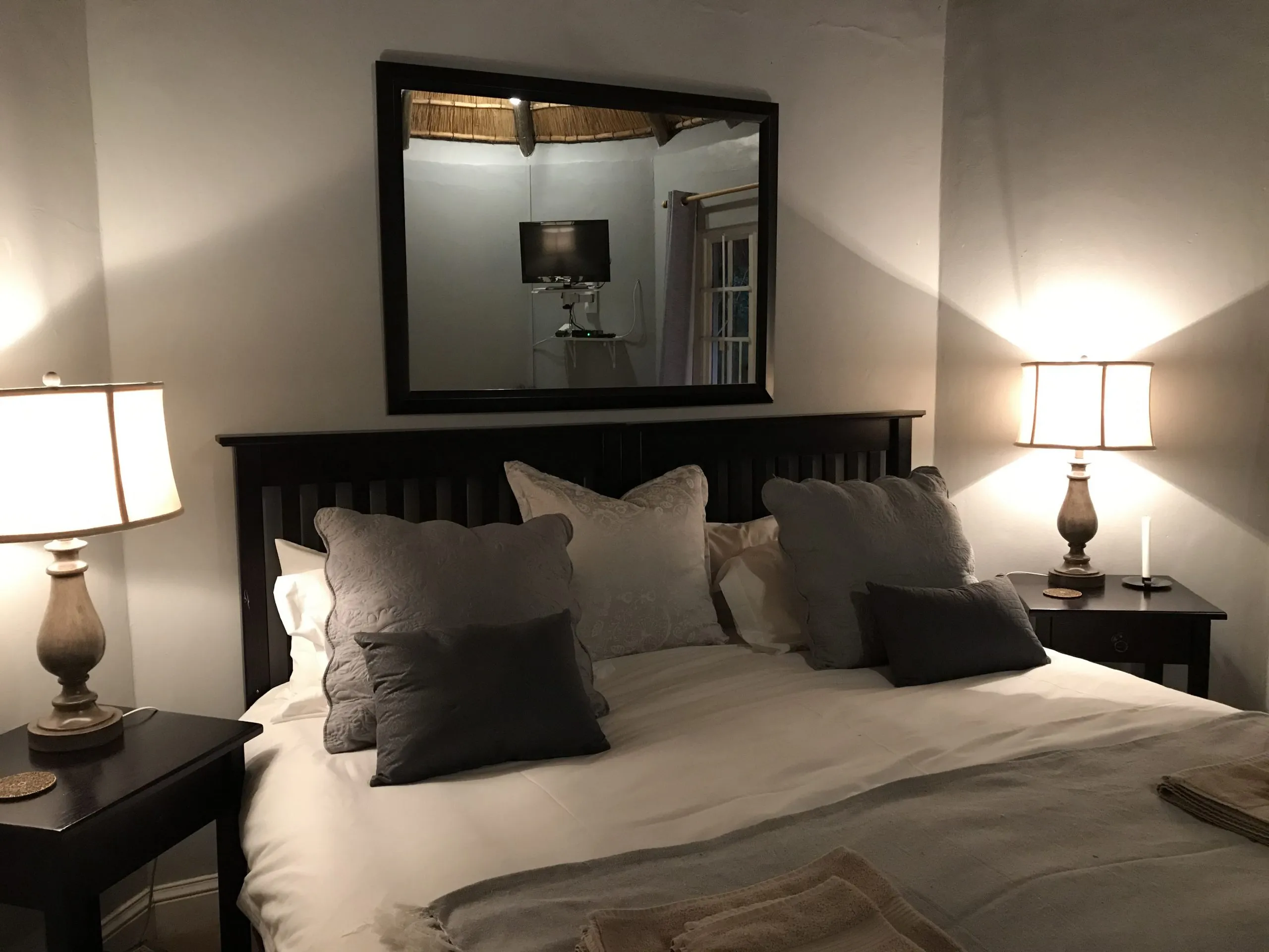Cozy bedroom with a large bed pillows lamps and a mirror above the headboard