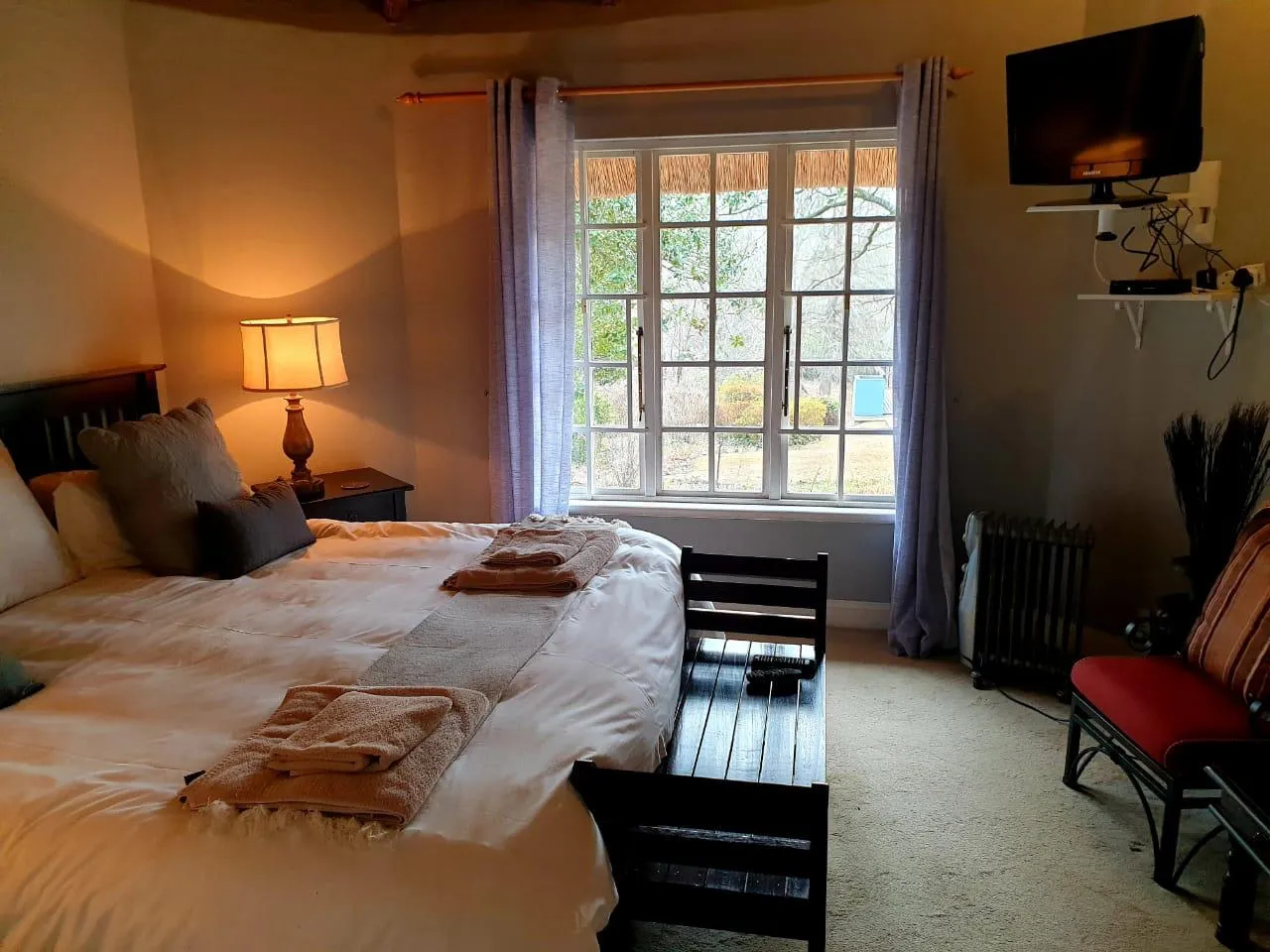 Cozy bedroom with large window bed bench and red chair