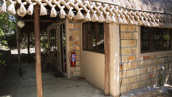 Stone building with thatched roof wooden porch and a fire extinguisher inside