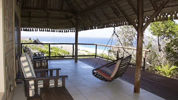 Wooden porch with chairs hammock and ocean view under a thatched roof