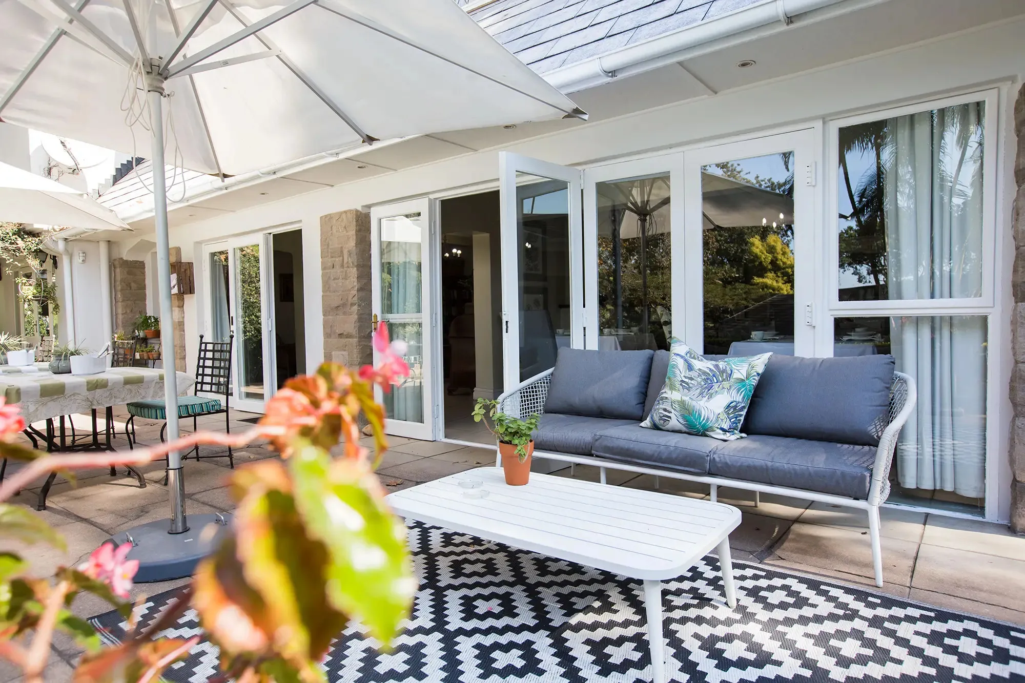 Patio with outdoor sofa coffee table and umbrella near a house