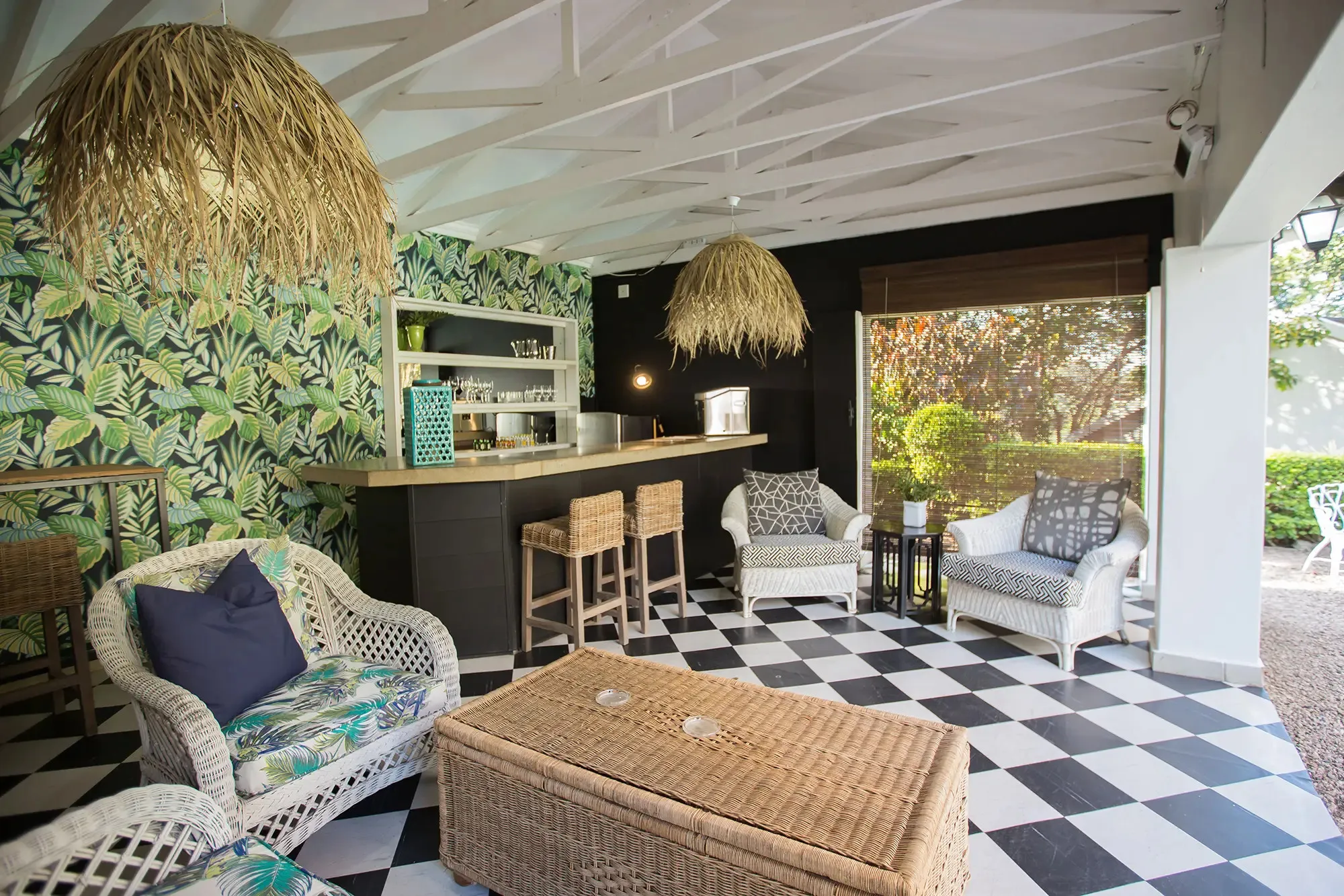 Tropicalthemed lounge with wicker furniture patterned wallpaper and blackandwhite checkered floor