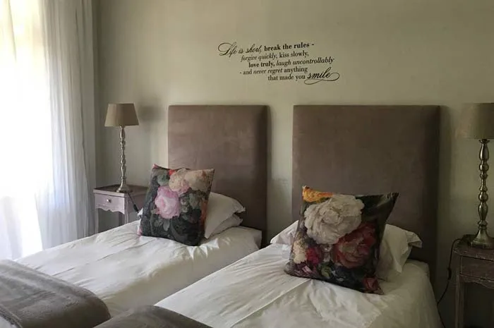 Two twin beds with floral pillows in a cozy bedroom with a wall quote