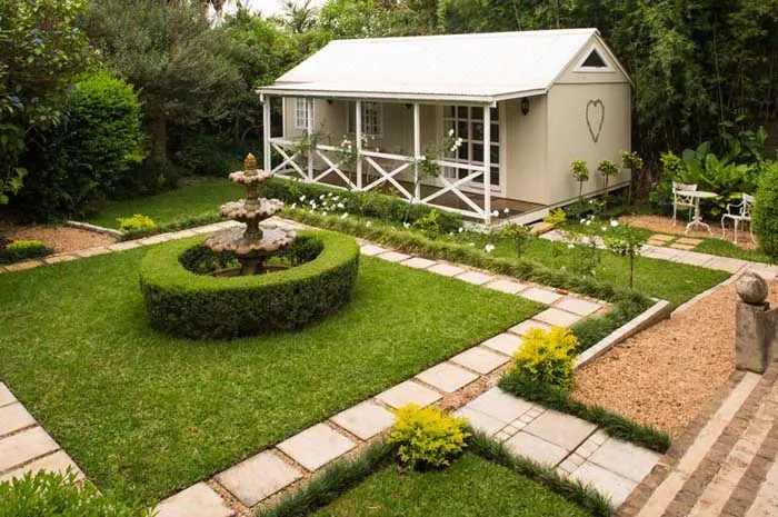 Small white cottage with a heart on the door in a manicured garden