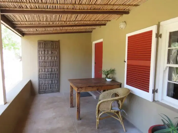 Wooden table and chair on a covered patio with a potted plant