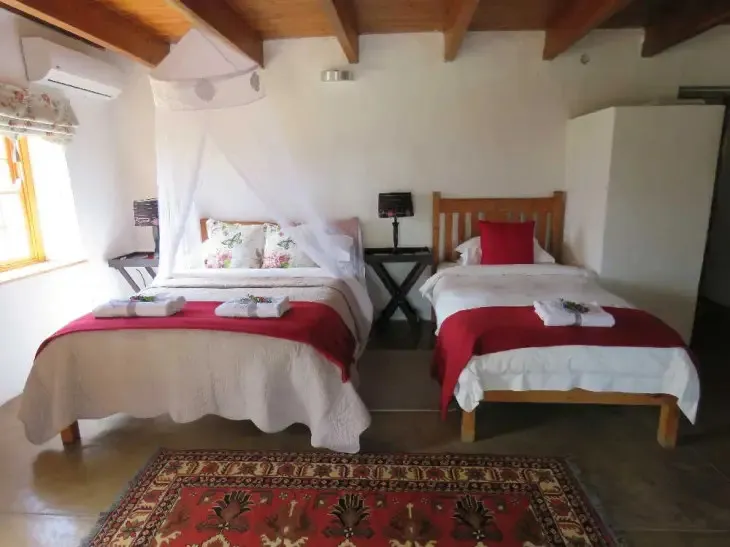 Two beds with red and white bedding in a cozy rustic bedroom