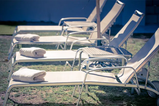 Several lounge chairs with towels on grass near a building