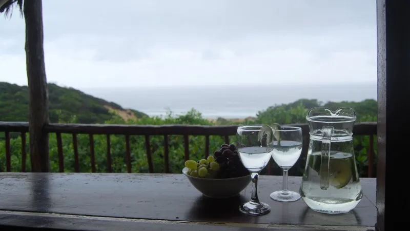 Two wine glasses and a water pitcher on a table with an ocean view