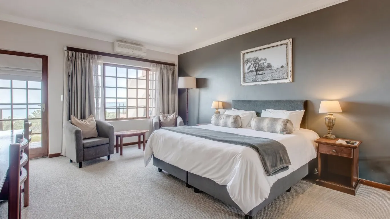 Modern bedroom with large bed armchair and scenic window view