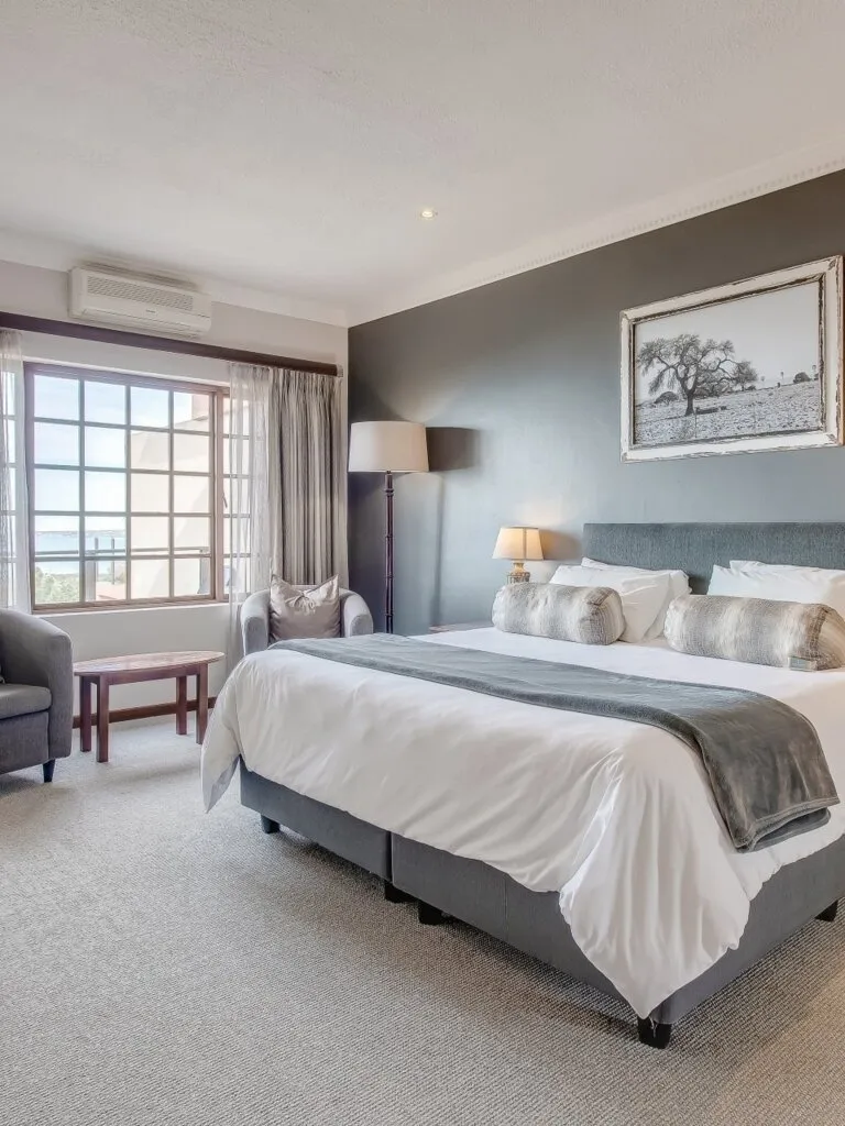 Modern bedroom with large bed armchair and framed picture on the wall