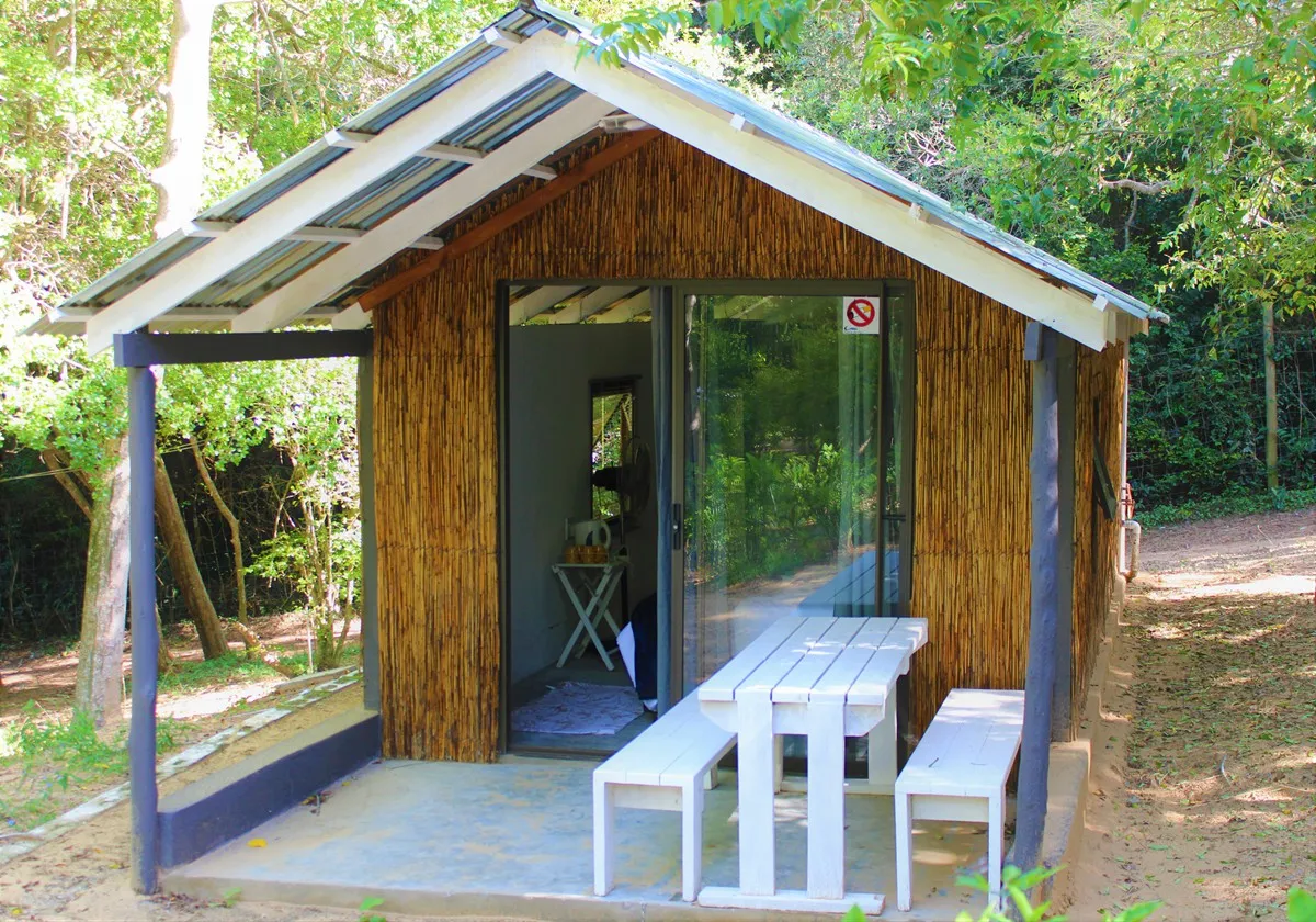 Wooden cabin with a porch and picnic table in a forested area