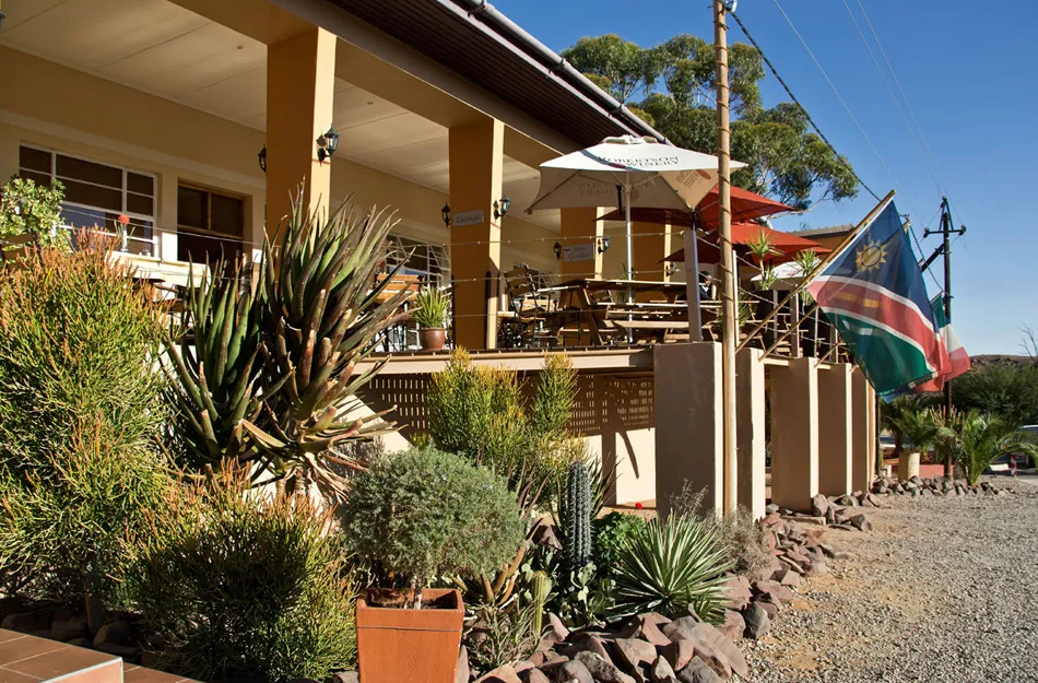 Outdoor seating area of a restaurant with plants and a flag in the background