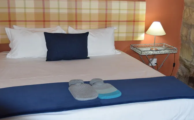 Bed with plaid headboard bedside lamp and two hot water bottles on blanket