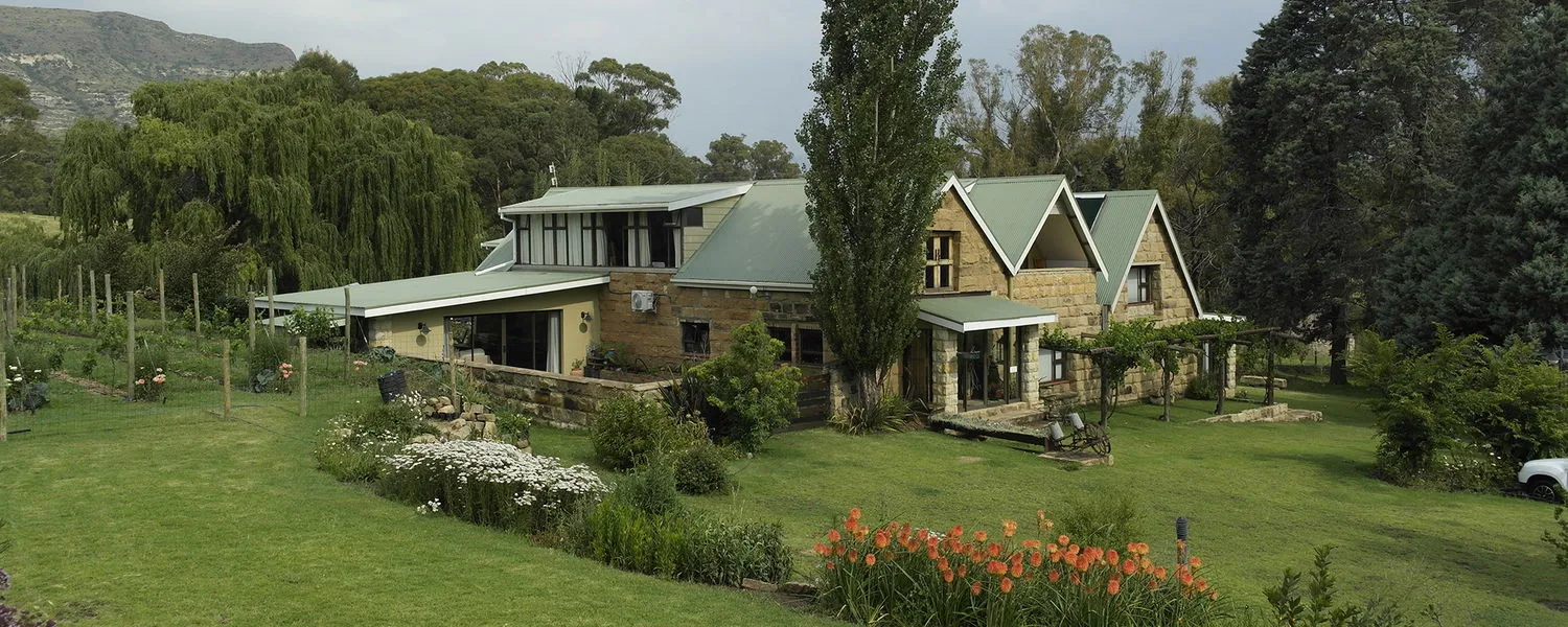Large house with garden trees and mountains in the background