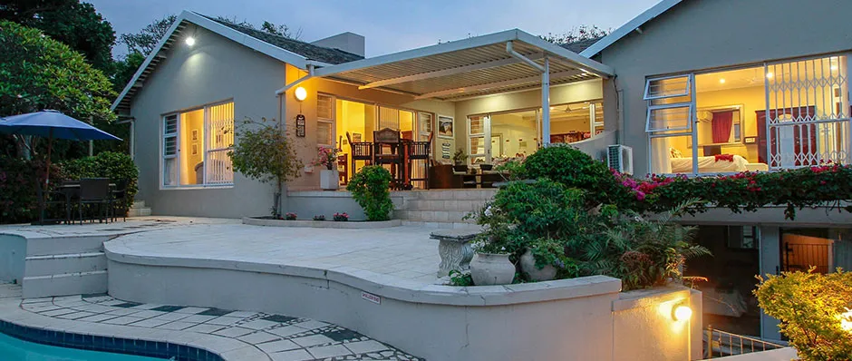 Modern house with pool and patio at dusk lights on inside