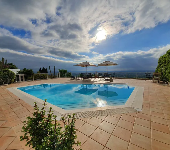 Swimming pool with lounge chairs and umbrellas under a partly cloudy sky