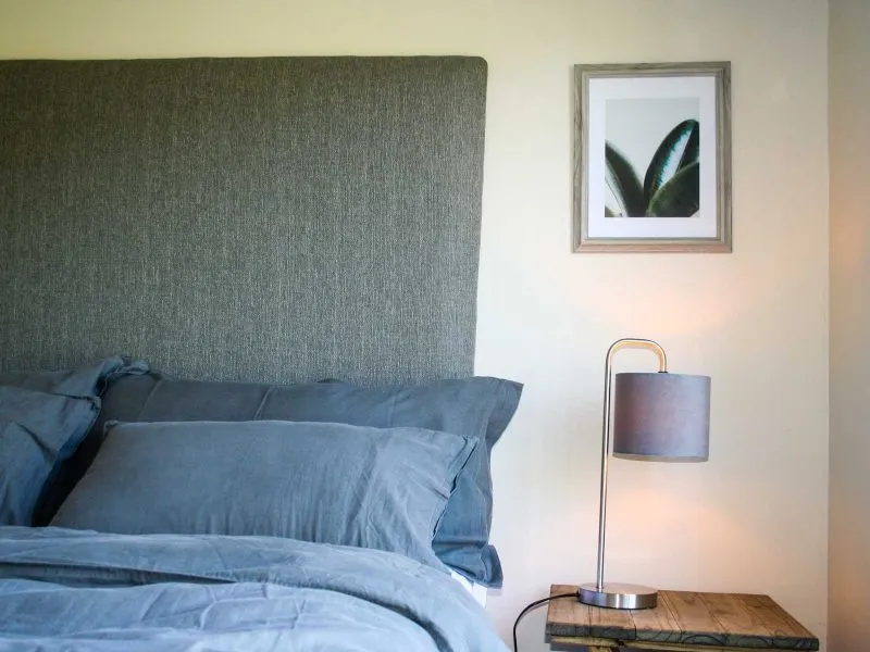 Bed with blue bedding nightstand with lamp and framed picture on the wall