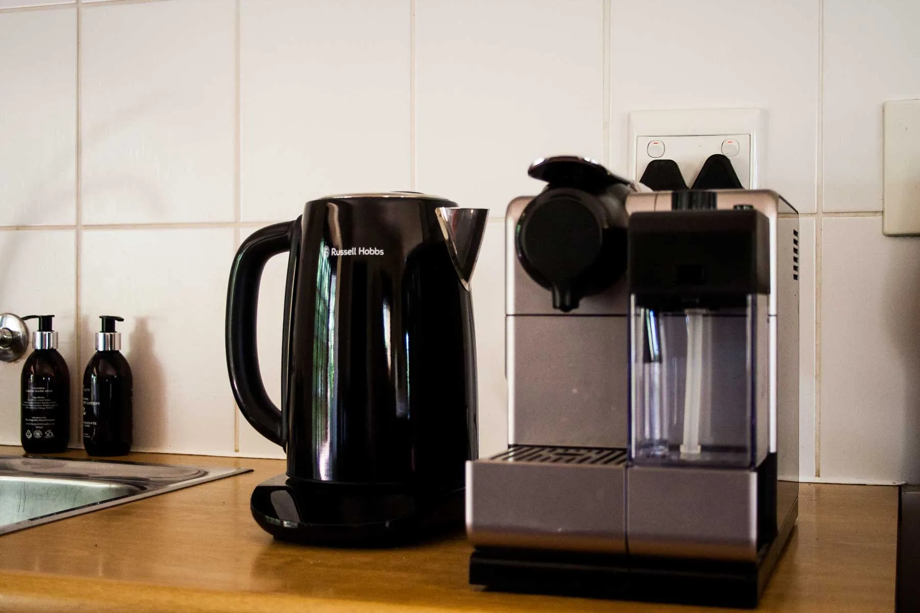 Black kettle and espresso machine on a kitchen counter with tiled backsplash