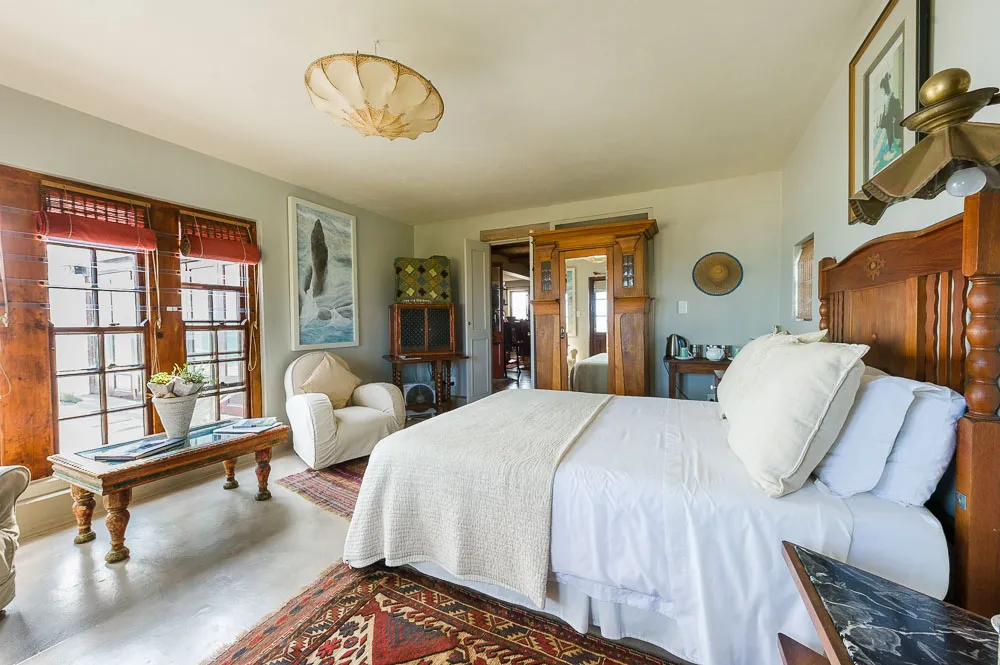 Cozy bedroom with large bed armchair and vintage decor near windows