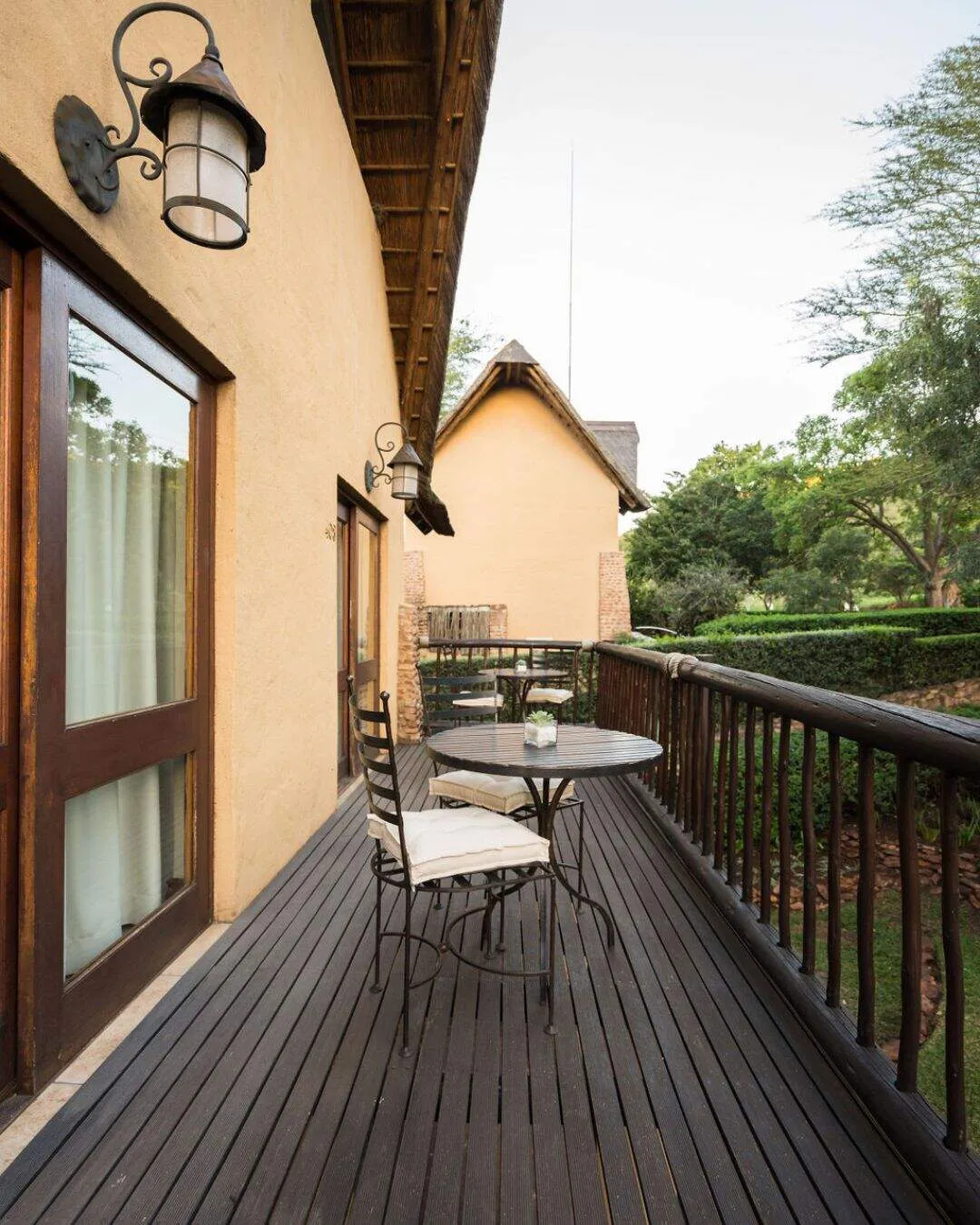 Wooden deck with table chairs and view of a house and greenery