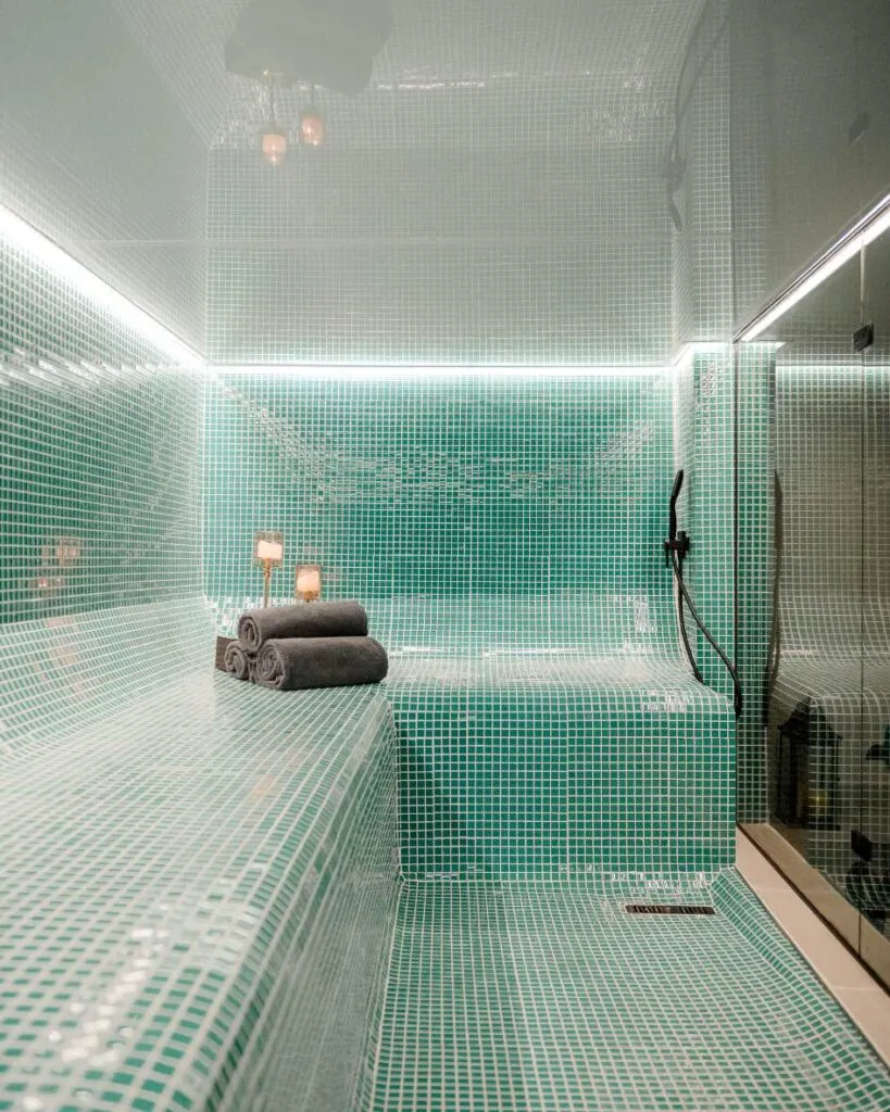 Modern tiled steam room with towels and a handheld shower