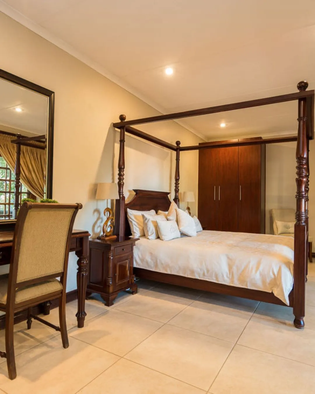 Fourposter bed in a bedroom with wooden furniture and tiled floor