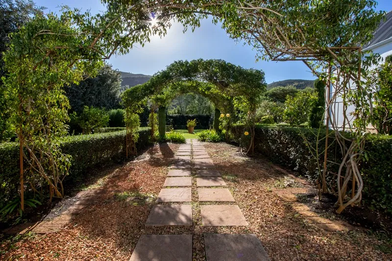 Garden path with stone tiles surrounded by greenery and archways with climbing plants