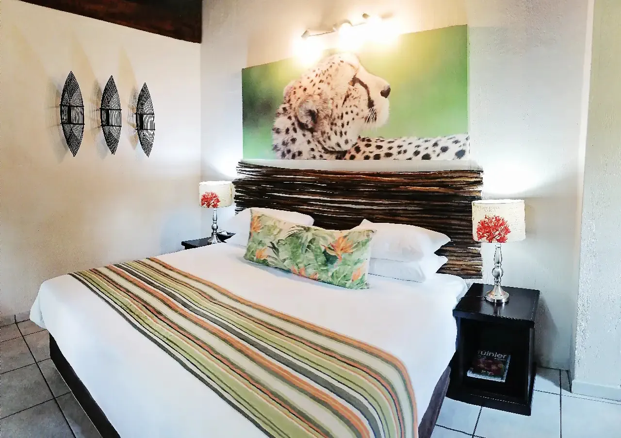 Bedroom with a bed green pillows and a large leopard print above the headboard