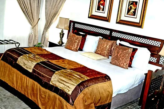 Elegant bedroom with a large bed decorative pillows and framed artwork on the wall