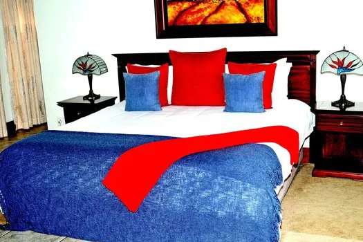 A bedroom with a bed featuring blue and red bedding and two bedside lamps