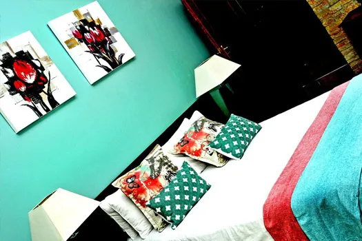 Bedroom with turquoise walls floral artwork and pillows on a bed