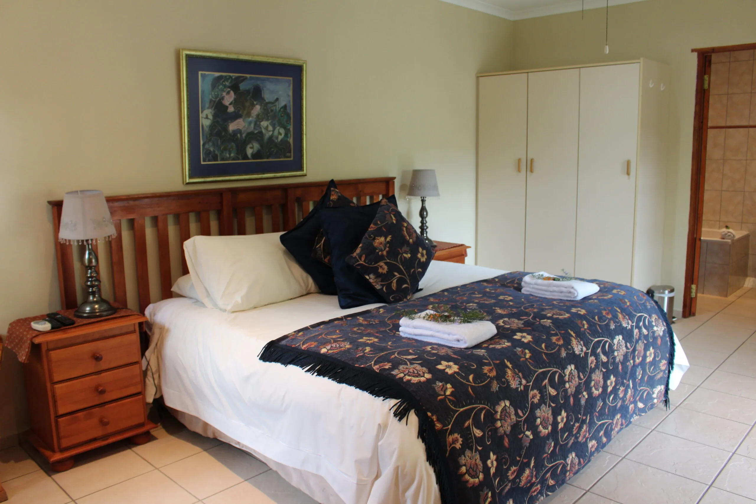 Cozy bedroom with a large bed floral blanket and wooden furniture