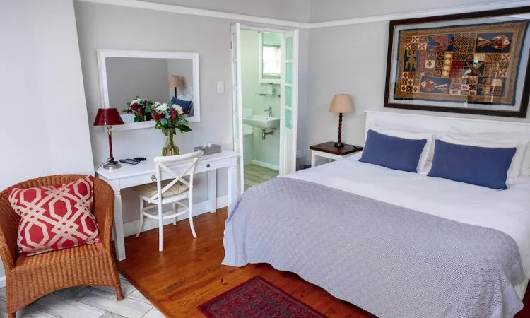 Cozy bedroom with a bed armchair desk and an open bathroom door