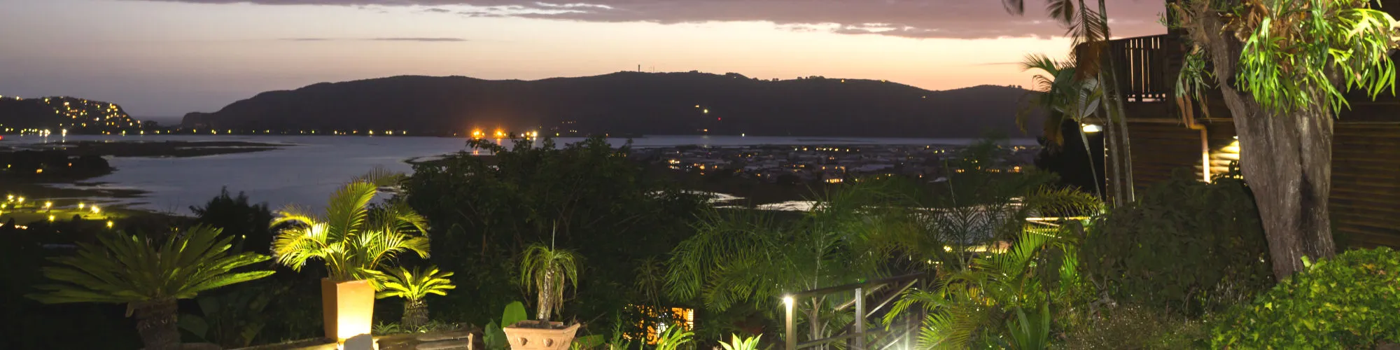 Evening view of a coastal town with illuminated plants and buildings