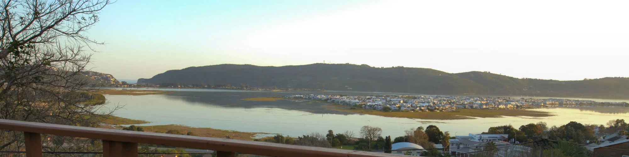 Scenic view of a lake with hills and buildings in the background