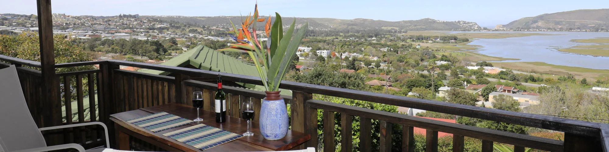 Wooden balcony with table chairs and view of town and river