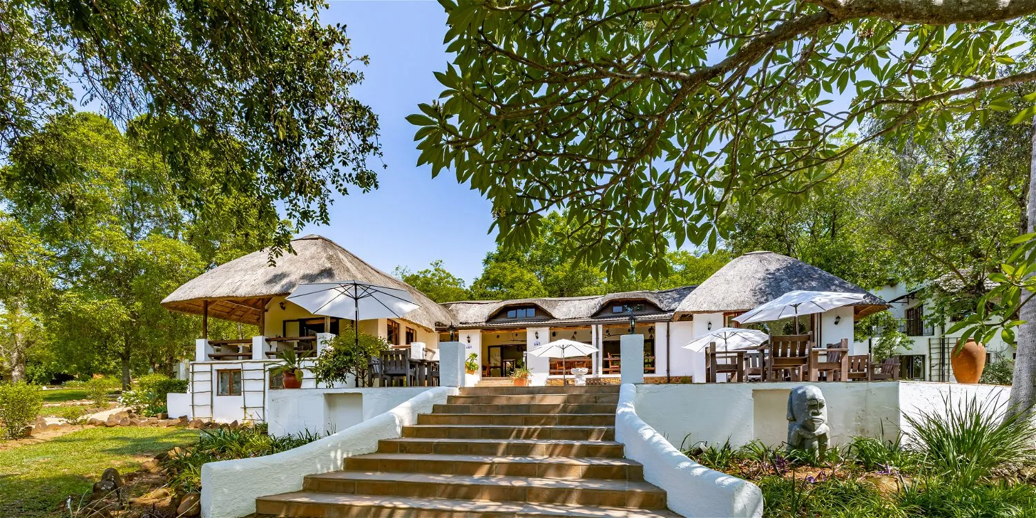 Outdoor restaurant with thatched roofs surrounded by trees and greenery