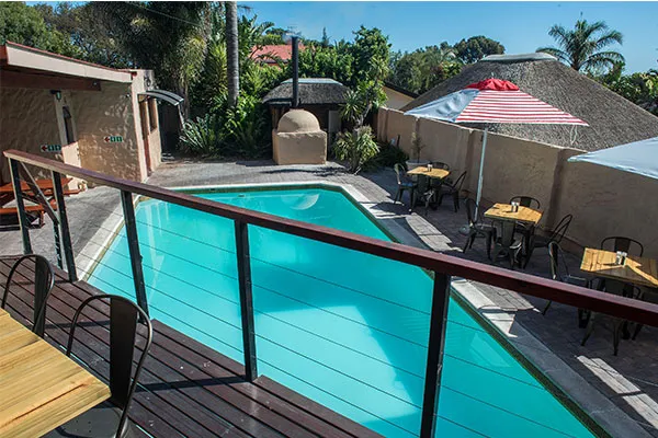 Swimming pool with deck chairs and tables in a tropical garden setting