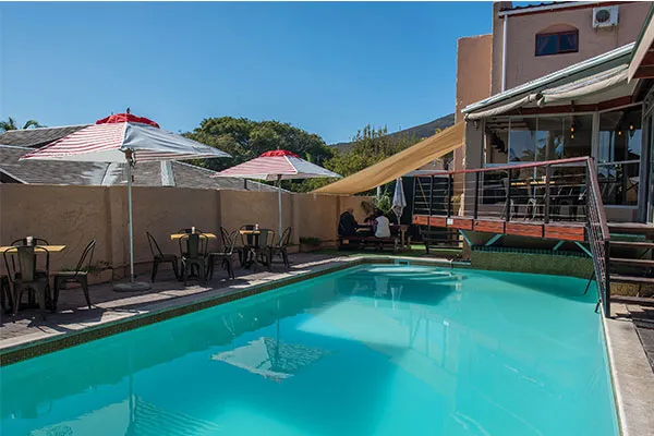 Outdoor pool with tables chairs and umbrellas at a resort
