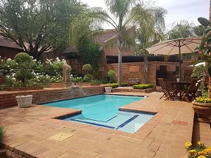 Swimming pool with a patio umbrella and garden in a residential setting