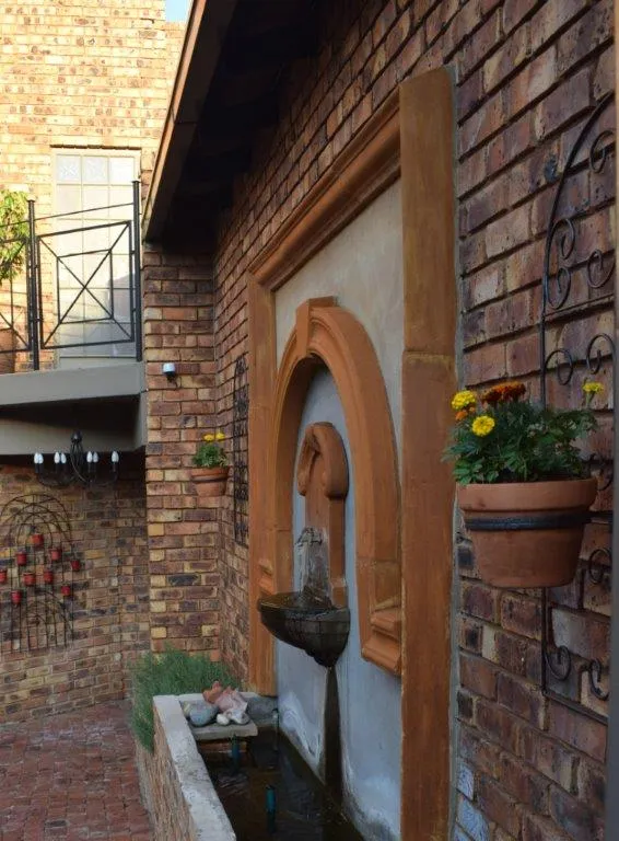 Brick courtyard with wall fountain potted flowers and balcony