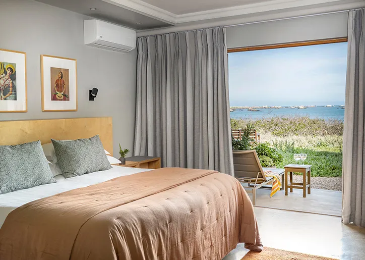 Bedroom with large window overlooking a garden and ocean view