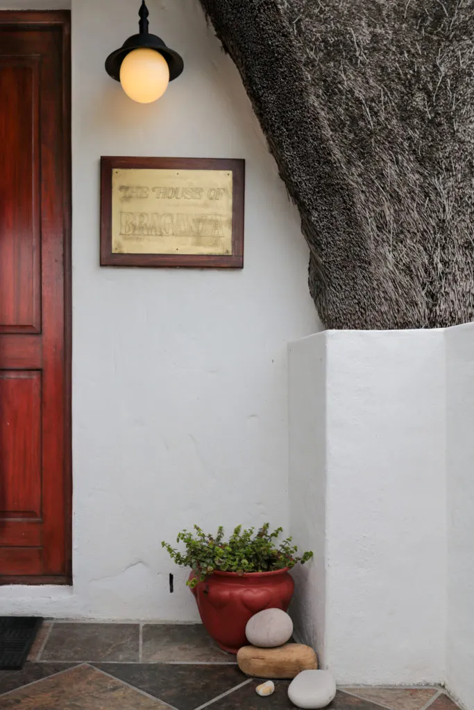 Red door plaque potted plant and stones beside a white wall